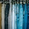 a rack of different colored jeans hanging from hooks