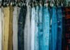 a rack of different colored jeans hanging from hooks