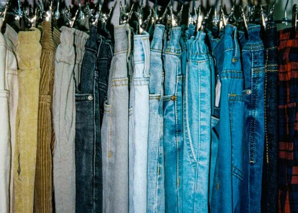 a rack of different colored jeans hanging from hooks