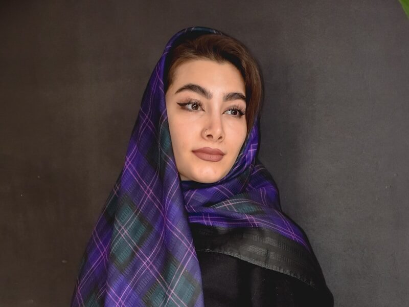 a woman wearing a purple and green plaid scarf