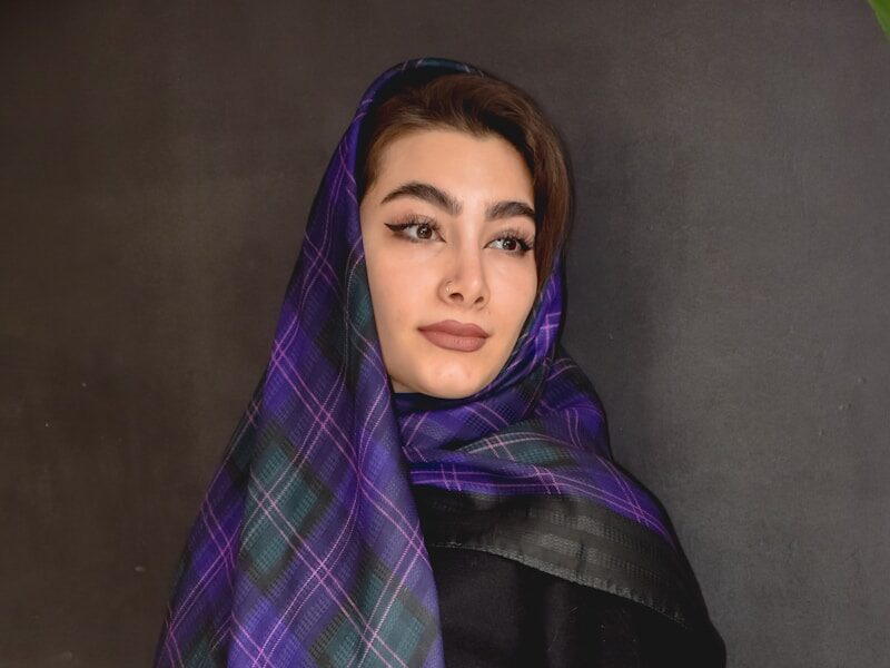 a woman wearing a purple and green plaid scarf