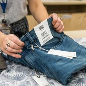 person in blue denim jeans holding white paper