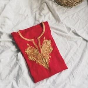 a red t - shirt with a gold embroidered design on it